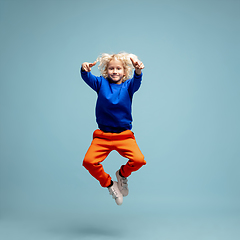 Image showing Happy curly boy isolated on blue studio background. Looks happy, cheerful, sincere. Copyspace. Childhood, education, emotions concept