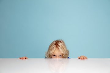 Image showing Happy curly boy isolated on blue studio background. Looks happy, cheerful, sincere. Copyspace. Childhood, education, emotions concept