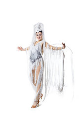 Image showing Beautiful young woman in carnival, stylish masquerade costume with feathers dancing on white studio background. Concept of holidays celebration, festive time, fashion