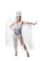 Image showing Beautiful young woman in carnival, stylish masquerade costume with feathers dancing on white studio background. Concept of holidays celebration, festive time, fashion