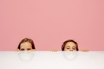 Image showing Happy children isolated on coral pink studio background. Look happy, cheerful, sincere. Copyspace. Childhood, education, emotions concept