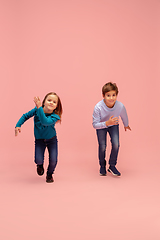 Image showing Happy children isolated on coral pink studio background. Look happy, cheerful, sincere. Copyspace. Childhood, education, emotions concept