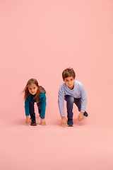 Image showing Happy children isolated on coral pink studio background. Look happy, cheerful, sincere. Copyspace. Childhood, education, emotions concept