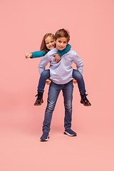 Image showing Happy children isolated on coral pink studio background. Look happy, cheerful, sincere. Copyspace. Childhood, education, emotions concept