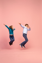 Image showing Happy children isolated on coral pink studio background. Look happy, cheerful, sincere. Copyspace. Childhood, education, emotions concept