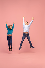 Image showing Happy children isolated on coral pink studio background. Look happy, cheerful, sincere. Copyspace. Childhood, education, emotions concept