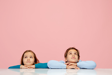 Image showing Happy children isolated on coral pink studio background. Look happy, cheerful, sincere. Copyspace. Childhood, education, emotions concept