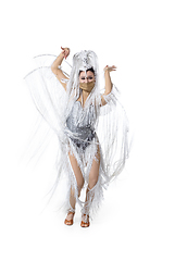 Image showing Beautiful young woman in carnival, stylish masquerade costume with feathers dancing on white studio background. Concept of holidays celebration, festive time, fashion