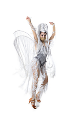 Image showing Beautiful young woman in carnival, stylish masquerade costume with feathers dancing on white studio background. Concept of holidays celebration, festive time, fashion