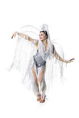 Image showing Beautiful young woman in carnival, stylish masquerade costume with feathers dancing on white studio background. Concept of holidays celebration, festive time, fashion