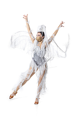 Image showing Beautiful young woman in carnival, stylish masquerade costume with feathers dancing on white studio background. Concept of holidays celebration, festive time, fashion