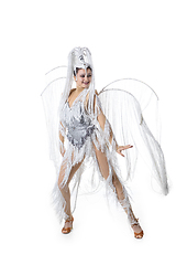 Image showing Beautiful young woman in carnival, stylish masquerade costume with feathers dancing on white studio background. Concept of holidays celebration, festive time, fashion