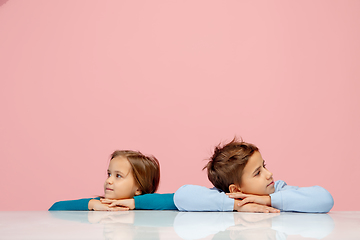 Image showing Happy children isolated on coral pink studio background. Look happy, cheerful, sincere. Copyspace. Childhood, education, emotions concept