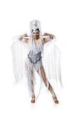 Image showing Beautiful young woman in carnival, stylish masquerade costume with feathers dancing on white studio background. Concept of holidays celebration, festive time, fashion