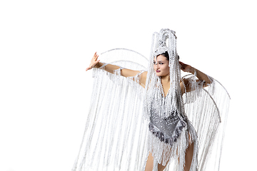 Image showing Beautiful young woman in carnival, stylish masquerade costume with feathers dancing on white studio background. Concept of holidays celebration, festive time, fashion