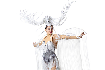 Image showing Beautiful young woman in carnival, stylish masquerade costume with feathers dancing on white studio background. Concept of holidays celebration, festive time, fashion