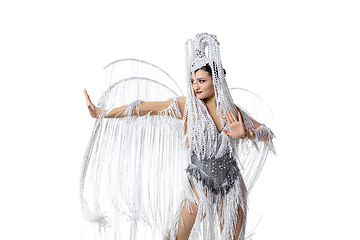 Image showing Beautiful young woman in carnival, stylish masquerade costume with feathers dancing on white studio background. Concept of holidays celebration, festive time, fashion