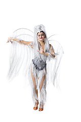 Image showing Beautiful young woman in carnival, stylish masquerade costume with feathers dancing on white studio background. Concept of holidays celebration, festive time, fashion