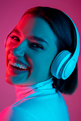 Image showing Caucasian woman\'s portrait isolated on pink studio background in multicolored neon light