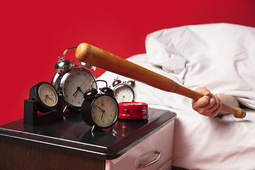 Image showing Man wakes up and he\'s mad at clock ringing, switches it off with baseball bat