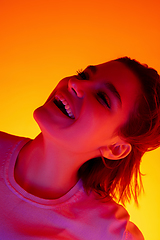 Image showing Caucasian woman\'s portrait isolated on orange studio background in multicolored neon light