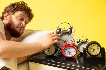 Image showing Man wakes up and he\'s mad at clock ringing, trying to switch it off, looks sleepy