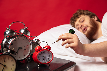 Image showing Man wakes up and he\'s mad at clock ringing, switches it off with dart