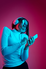 Image showing Caucasian woman\'s portrait isolated on pink studio background in multicolored neon light