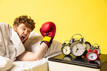 Image showing Man wakes up and he\'s mad at clock ringing, switches it off with the boxing glove