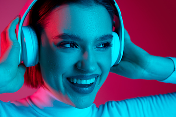 Image showing Caucasian woman\'s portrait isolated on pink studio background in multicolored neon light