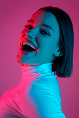 Image showing Caucasian woman\'s portrait isolated on pink studio background in multicolored neon light