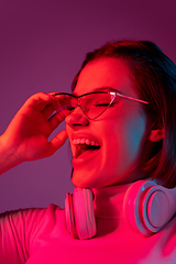 Image showing Caucasian woman\'s portrait isolated on pink studio background in multicolored neon light