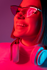 Image showing Caucasian woman\'s portrait isolated on pink studio background in multicolored neon light