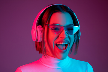 Image showing Caucasian woman\'s portrait isolated on pink studio background in multicolored neon light