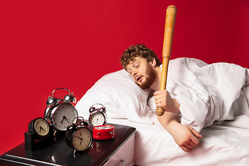 Image showing Man wakes up and he\'s mad at clock ringing, switches it off with baseball bat