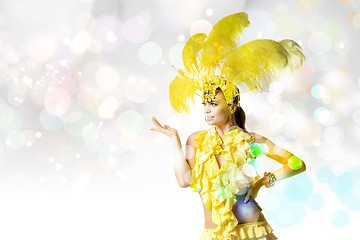 Image showing Beautiful young woman in carnival, stylish masquerade costume with feathers dancing on white studio background with shining bokeh