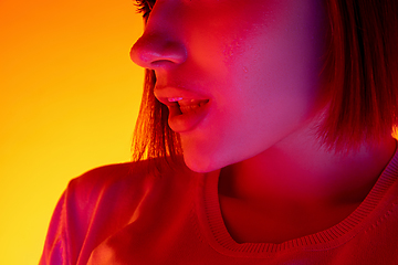 Image showing Caucasian woman\'s portrait isolated on orange studio background in multicolored neon light