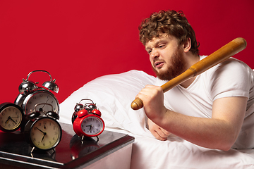 Image showing Man wakes up and he\'s mad at clock ringing, switches it off with baseball bat