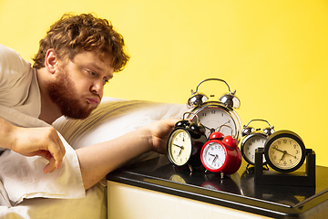 Image showing Man wakes up and he\'s mad at clock ringing, trying to switch it off, looks sleepy