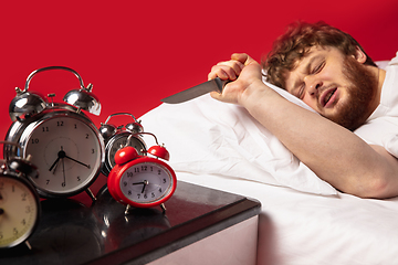Image showing Man wakes up and he\'s mad at clock ringing, switches it off with kitchen knife
