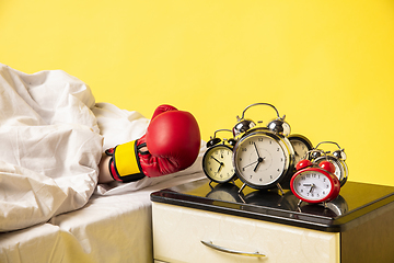 Image showing Man wakes up and he\'s mad at clock ringing, switches it off with the boxing glove