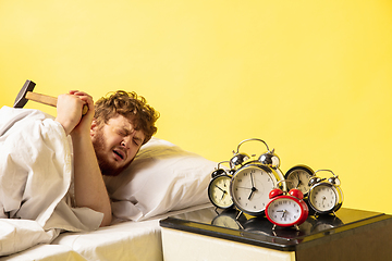 Image showing Man wakes up and he\'s mad at clock ringing, switches it off with the hammer