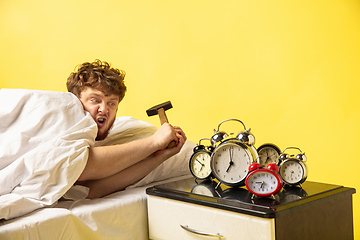 Image showing Man wakes up and he\'s mad at clock ringing, switches it off with the hammer