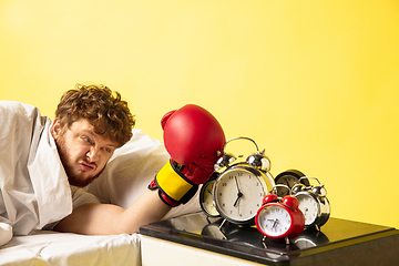 Image showing Man wakes up and he\'s mad at clock ringing, switches it off with the boxing glove