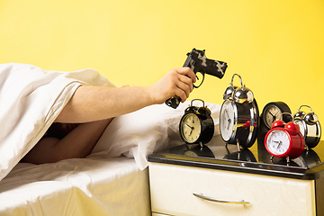 Image showing Man wakes up and he\'s mad at clock ringing, switches it off with the gun