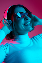 Image showing Caucasian woman\'s portrait isolated on pink studio background in multicolored neon light