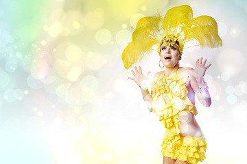 Image showing Beautiful young woman in carnival, stylish masquerade costume with feathers dancing on white studio background with shining bokeh