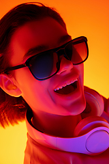 Image showing Caucasian woman\'s portrait isolated on orange studio background in multicolored neon light