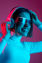 Image showing Caucasian woman\'s portrait isolated on pink studio background in multicolored neon light