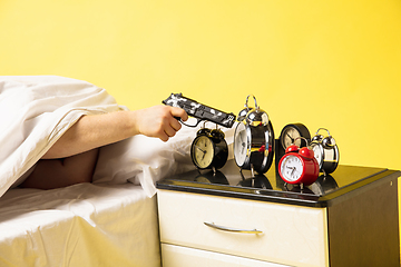 Image showing Man wakes up and he\'s mad at clock ringing, switches it off with the gun